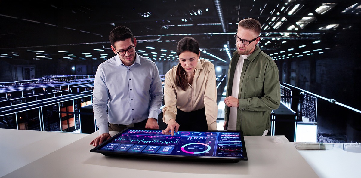 Three professionals analyzing partner performance metrics on a large interactive touchscreen in a modern workspace.