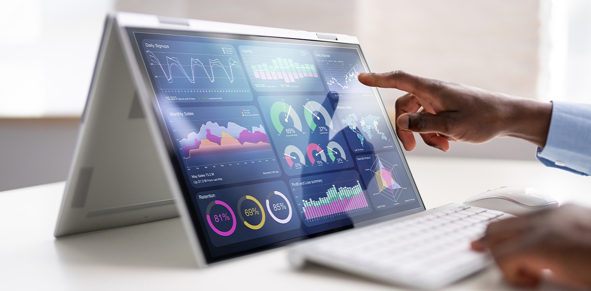 Partner using a touchscreen laptop to review analytics dashboards with performance charts and KPIs.