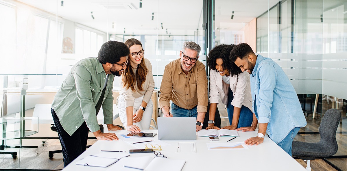 Team collaborating around a laptop on PartnerOps strategy and planning.